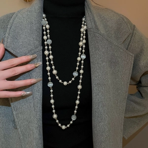 Détail d'un collier à deux rangs avec perles et œil de chat sur un manteau en laine