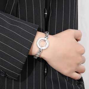 Detail of silver chain bracelet with heart-shaped cutout circle on a suit-clad model