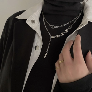 Macro detail of a layered silver pig-nose necklace paired with gold minimalist rings
