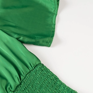 Detailed macro view of the glossy green satin fabric with intricate shirring texture