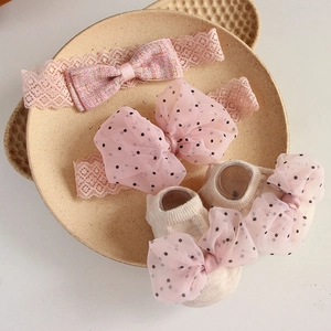 Pink lace bow headband and cream baby socks set displayed on a ceramic plate