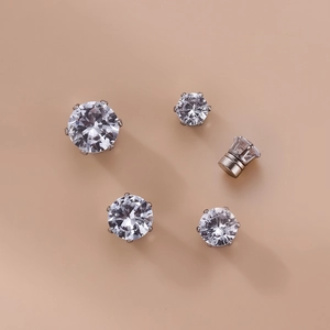 Macro view of six-prong cubic zirconia magnetic earrings on a beige background