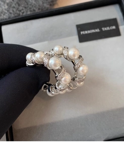 Close-up of elegant silver-tone C-shaped earrings with pearls and cubic zirconia
