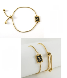Détail du bracelet réglable en acier doré avec breloques alphabétiques en émail noir