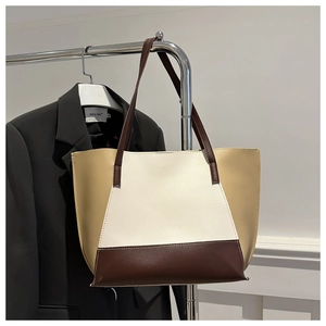 Detailed view of color-block tote bag hanging with a suit for a stylish minimalist look