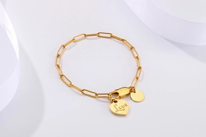 Detail of golden heart charm with Love engraving on paperclip link bracelet
