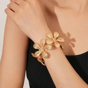 Exquisites goldfarbenes Blumenarmband mit strukturierten Metallblüten und Kristallsteinen