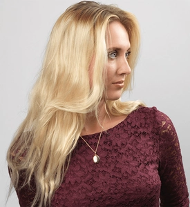 Close-up of a gold starburst flip pendant necklace worn over a purple lace top