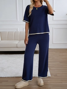 Detail view of navy blue knit set showing beige contrast trim on sleeves and leg cuffs