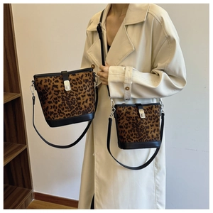 Detail view of large and small leopard print bucket bags with leather trim on model