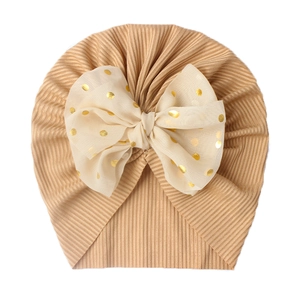 Close-up of ribbed baby turban hat featuring a gold polka dot chiffon bow detail