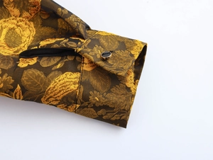 Detailed close-up of vintage golden floral jacquard sleeve cuff with black button