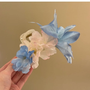 Détail de fleurs en soie rose et bleue sur une pince à cheveux en acrylique poli