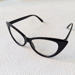 Side view of black cat-eye kids sunglasses on a textured cream background for sun protection