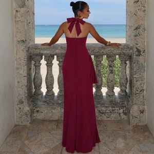 Detail of burgundy backless halter dress featuring a large bow on an ocean balcony