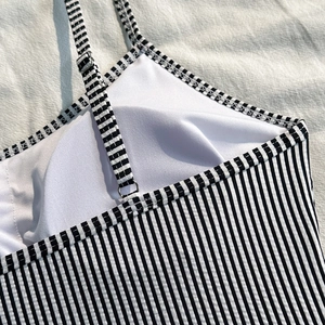 Detail of black and white striped swimsuit with adjustable metal buckles and built-in pads