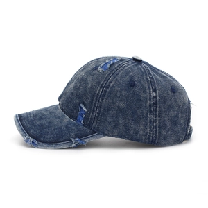 Close-up of distressed dark blue denim baseball cap with vintage frayed hole details