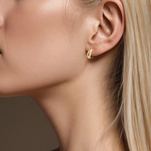 Vista dettagliata di un orecchino a goccia d'oro minimalista indossato da una modella