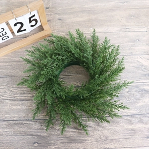 Gros plan d'une couronne de pin artificiel de 33cm sur bois avec calendrier de Noël