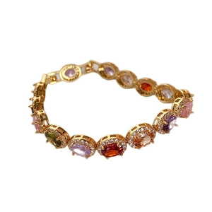Elegant gold bracelet with multicolored oval stones and zircon halo setting on white background