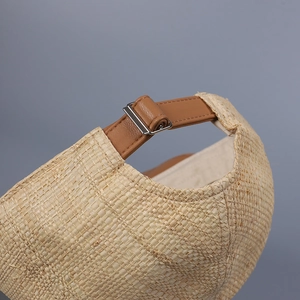 Detail of raffia baseball cap featuring adjustable brown leather strap and silver buckle