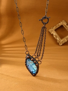 Macro view of teardrop labradorite stone with blue glow and antique bronze toggle chain