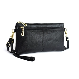 Detail of black pebbled leather crossbody bag featuring triple gold zipper compartments