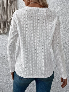Detail shot of the geometric hollow-out lace texture on the back of a white long sleeve top