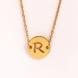 Détail du collier doré en acier inoxydable avec pendentif rond évidé de la lettre R