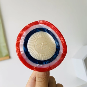 Detailed close-up of a tricolor acetic acid hair claw with a vintage sun relief motif