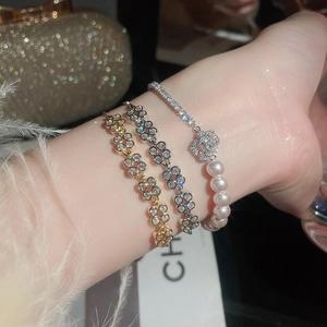 Detailed view of layered bracelets with zircon flowers and pearls on a model's wrist