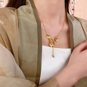 Detail of gold flower pendant with tassel fringe on a necklace worn by model