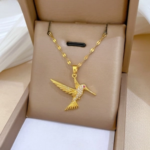 Macro detail of hummingbird pendant with gold plating and sparkling zircon inlay