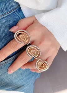 Close-up of 18k gold and silver geometric spiral rings worn on a model's hand