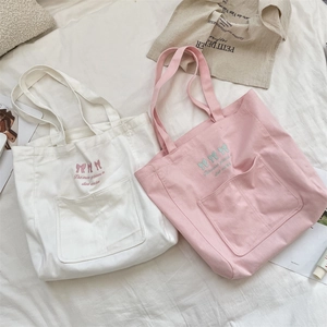 Gros plan détaillé des nœuds brodés et de la citation sur le sac cabas en toile