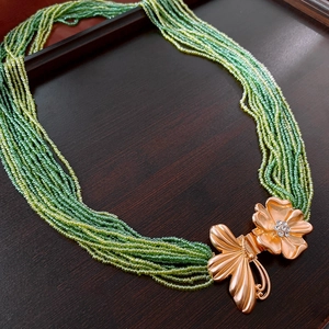 Détail de la chaîne de corps en perles vertes avec boucle papillon fleurie en strass