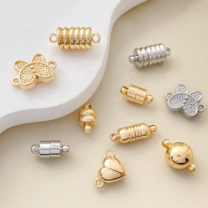 Magnetische Schmuckverschlüsse in Gold und Silber, Herz- und Kugelform auf Lederhintergrund
