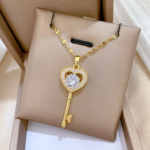 Macro detail of gold heart key pendant with crystals on a beige gift box cushion
