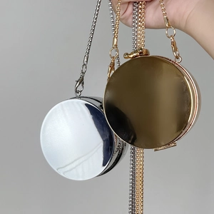 Polished gold and silver round metal clutch bags with fine chain straps held by hand