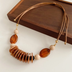Detail of vintage leather necklace with brown and beige beads on white surface