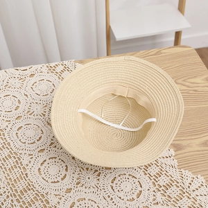 Detail of breathable straw sun hat featuring a secure white elastic windproof chin strap