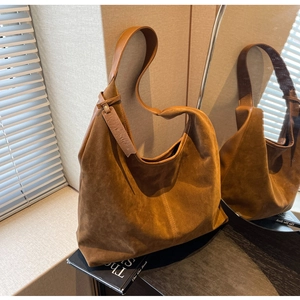 Detail of brown suede hobo bag with Sonno Fashion logo tag on a vintage book