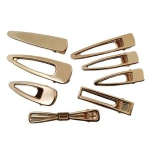Set of gold hollow metal hair clips in teardrop and bow shapes on a white background