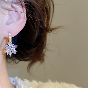 Detail of flower hoop earrings with purple marquise stones and crystals in gold setting
