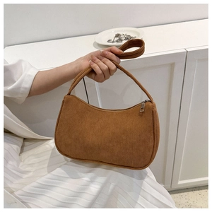 Detail view of the brown corduroy fabric texture on a minimalist baguette shoulder bag