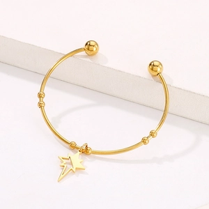 Macro shot of gold hollow star charm and bead details on the polished titanium steel bangle