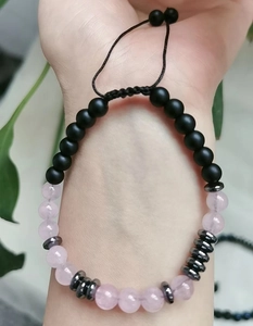 Dettaglio del bracciale con perle codice Morse, quarzo rosa e pietre nere sul polso