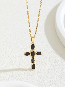 Close-up of gold-plated cross necklace with black oval zircon and clear pavé crystals