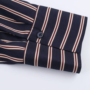 Detail of single-button shirt cuff with navy blue and red vertical stripes on fine fabric