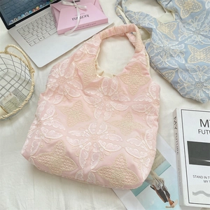 Detailed embroidery of white butterflies on a soft pink lace tote bag texture